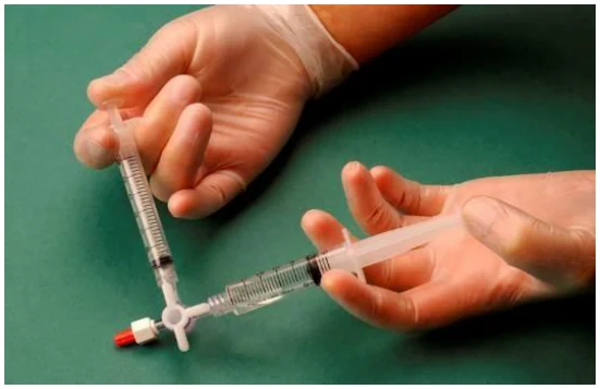 Hands holding a syringe with a red cap
Description automatically generated